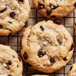 A close up image of six of the life changing tahini chocolate chip cookies, laid out on a wire cooling rack