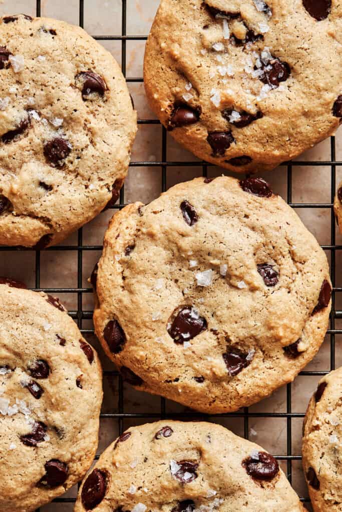 A close up image of six of the life changing tahini chocolate chip cookies, laid out on a wire cooling rack