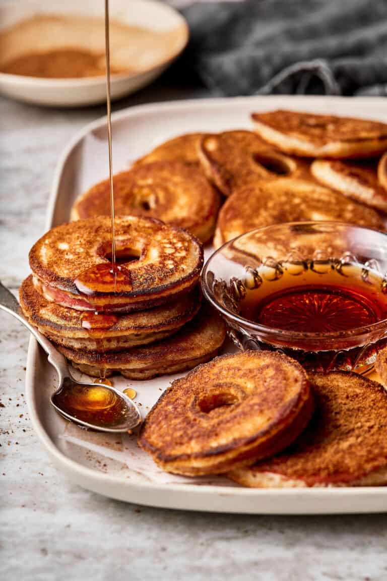 A tray of healthy apple pancake dippers, with apple syrup being drizzled on top of them