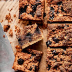 The grain-free blueberry coffee cake, cut into squares, and laying out on a sheet of parchment paper