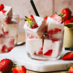 A cup of the high protein strawberry yogurt cubes, sitting on top of a marble cutting board