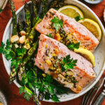 A big bowl of the sheet pan lemon-herb salmon with asparagus. A few slices of lemon rests in the bowl