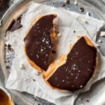 A giant peanut butter chocolate rice cake, broken in half, on a sheet of parchment paper on a baking sheet