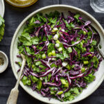 A large bowl of the Copycat Erewhon Cabbage Slaw, sitting on a countertop with a large fork stuck in it