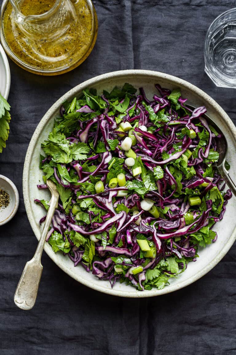 A large bowl of the Copycat Erewhon Cabbage Slaw, sitting on a countertop with a large fork stuck in it