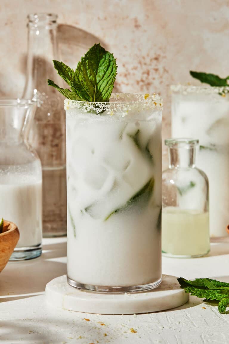 A tall glass of the coconut mojito mocktail. sitting on a countertop