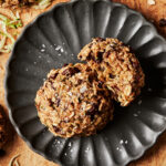 A plate, sitting on a countertop, with two of the vegan chocolate chip zucchini breakfast cookies sitting on it