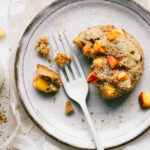 A plate topped with a fork and one of the single serving peach walnut scones