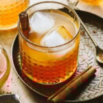 A glass of the Apple Cider Whiskey Smash, sitting on a tray on a countertop
