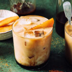 A glass of the apple crisp cold brew latte, sitting on a countertop