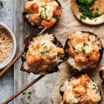 A tray of the viral baked salmon sushi cups, sitting on a countertop, with chopsticks holding up one of the cups