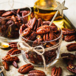 A jar of the bourbon pecans, sitting on a countertop with a ribbon tied around them