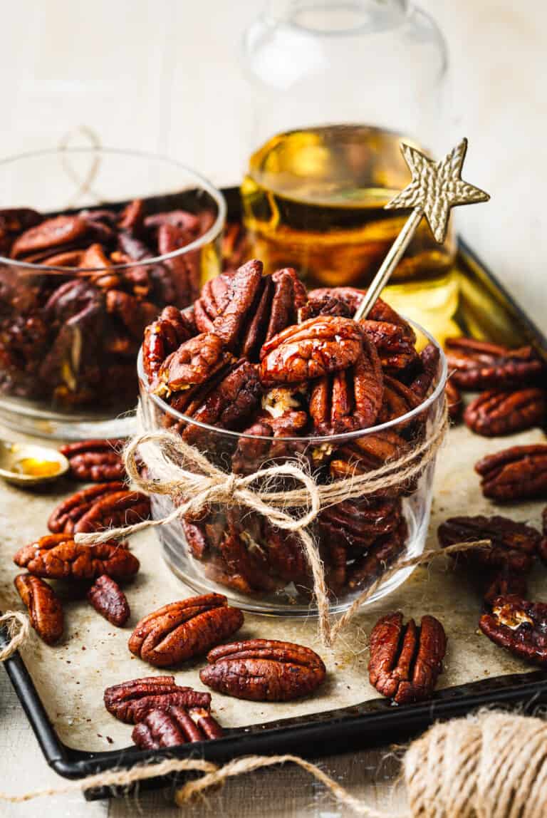 A jar of the bourbon pecans, sitting on a countertop with a ribbon tied around them