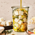 A jar of the 5 minute marinaded feta, with olive oil being actively poured into it