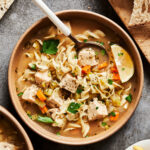A bowl of the cozy turkey noodle soup, sitting on a countertop