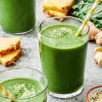 A glass of the ultimate kale smoothie, sitting on a countertop with other smoothie ingredients
