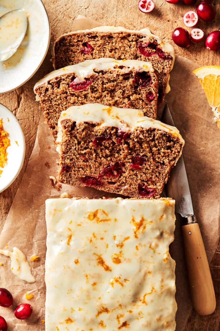 The best ever cranberry orange loaf, sitting on a countertop, sliced into a few slices