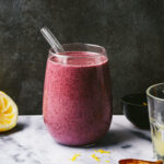 A glass of the blueberry lemon pie smoothie, sitting on a countertop