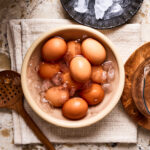 A bowl of the perfect hard boiled eggs, sitting on a countertop