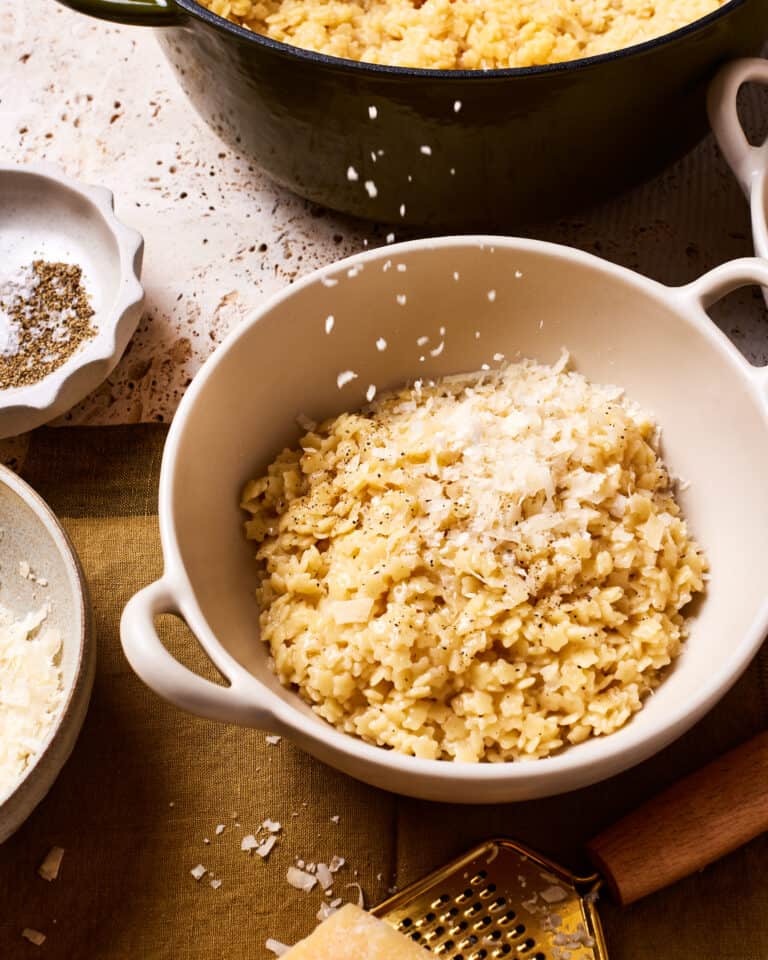 A big bowl of the pastina, with parmesan cheese actively being sprinkled on top of it