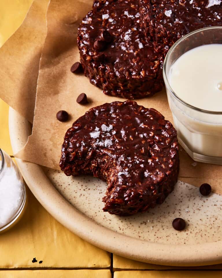 A close-up image of one of the Star Crunch clusters, with a bite taken out of it, sitting on a plate alongside a glass of milk