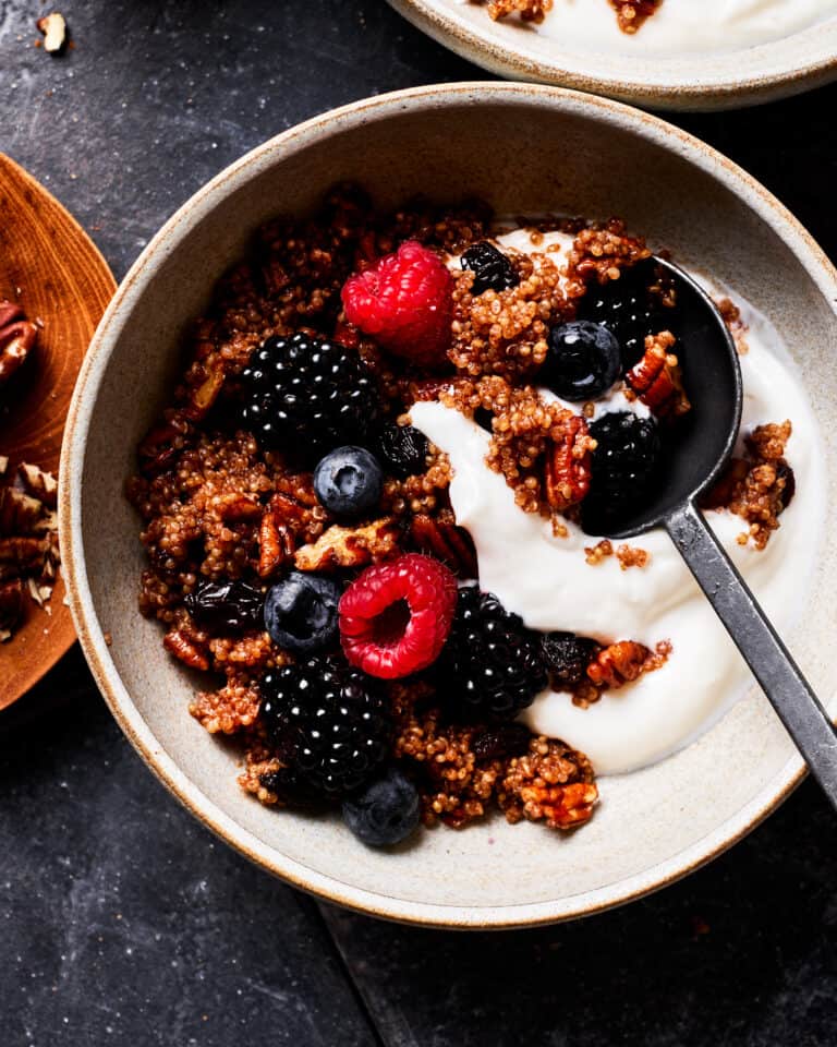 A close-up image of a bowl of the breakfast quinoa, served with yogurt and berries