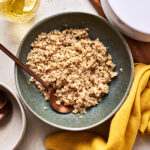 A bowl of the perfect quinoa, sitting on a countertop with a spoon inside of it