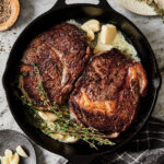 A cast iron skillet, filled with two of the perfect pan seared steaks