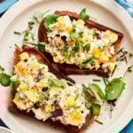 A plate of the one bowl healthy egg salad, spread across two pieces of toast, sitting on a countertop