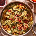 A big pot of the cucumber sweet pepper salad, sitting on a countertop with spoons sitting in the bowl