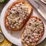 Two pieces of toast with the easy 10 minute tuna salad spread on top, sitting on a plate on a countertop