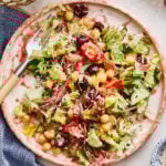A bowl of the Italian chopped salad, sitting on a countertop with the spoon inside of it