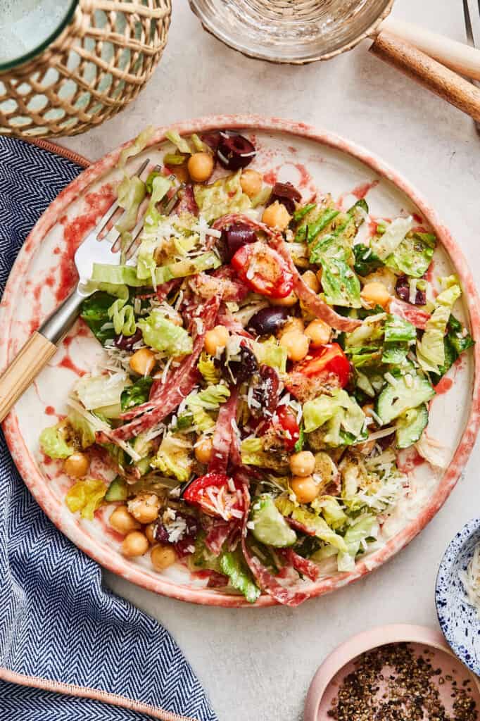 A bowl of the Italian chopped salad, sitting on a countertop with the spoon inside of it