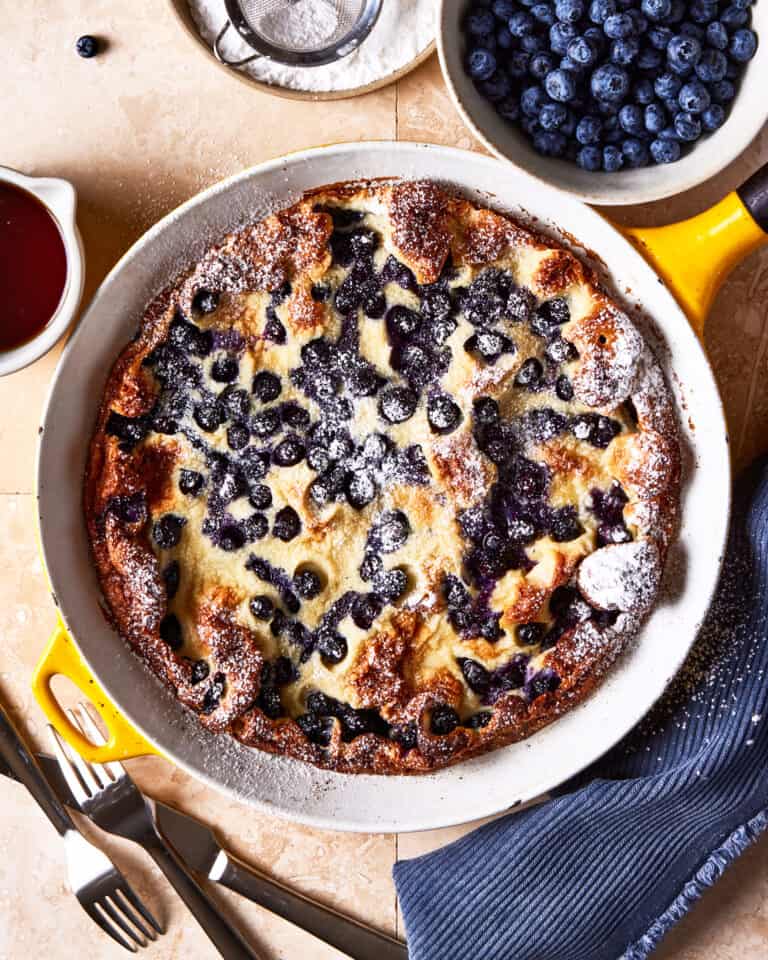 A pie dish, filled with the blueberry lemon dutch baby, sitting on a countertop