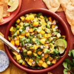 A big bowl of the mango avocado salsa, sitting on a countertop surrounded by tortilla chips
