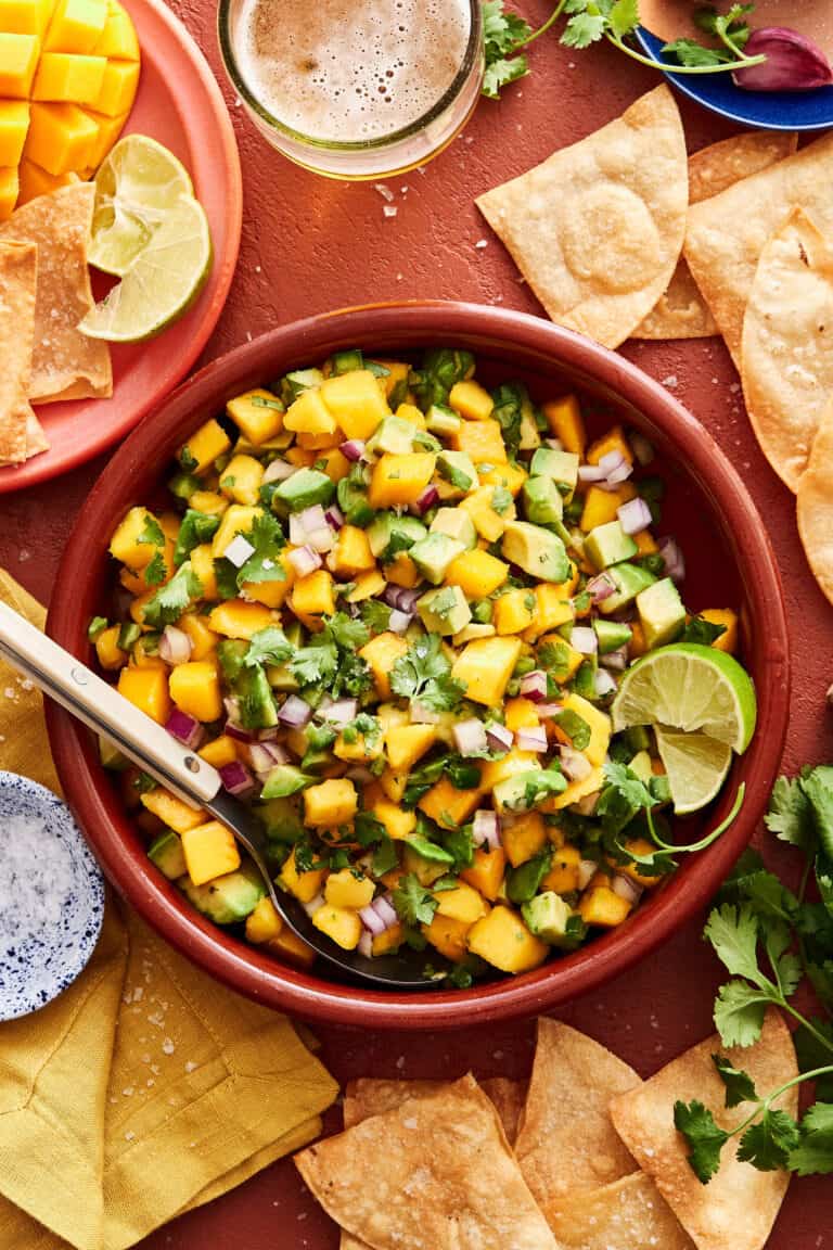 A big bowl of the mango avocado salsa, sitting on a countertop surrounded by tortilla chips