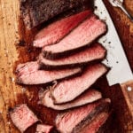 A close-up image of the sliced tri tip roast, sitting on a cutting board with a knife next to it