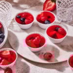 A plate full of the quick and easy healthy jello shots, sitting on a countertop surrounded by fresh fruit