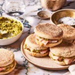 A plate full of the green onion pesto ham and cheese breakfast sandwiches, sitting on a plate on a countertop
