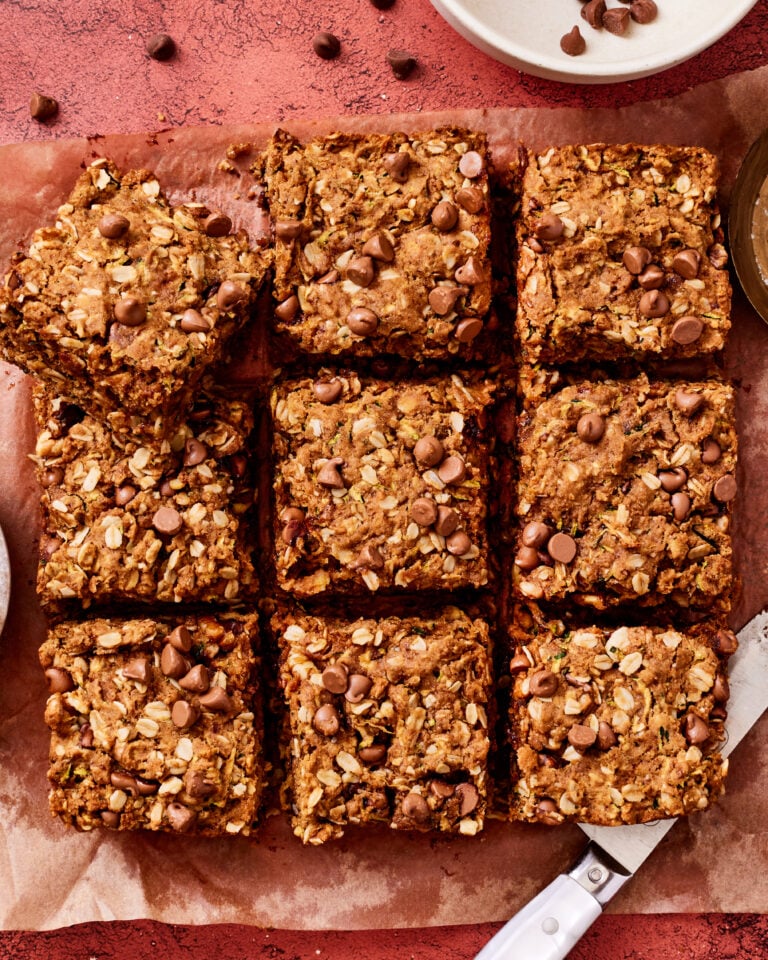 The one bowl oatmeal chocolate chip zucchini bars, sliced into squares and laid out on a sheet of parchment paper