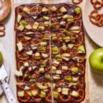 A tray of the caramel apple bark, sitting on a countertop and broken into pieces