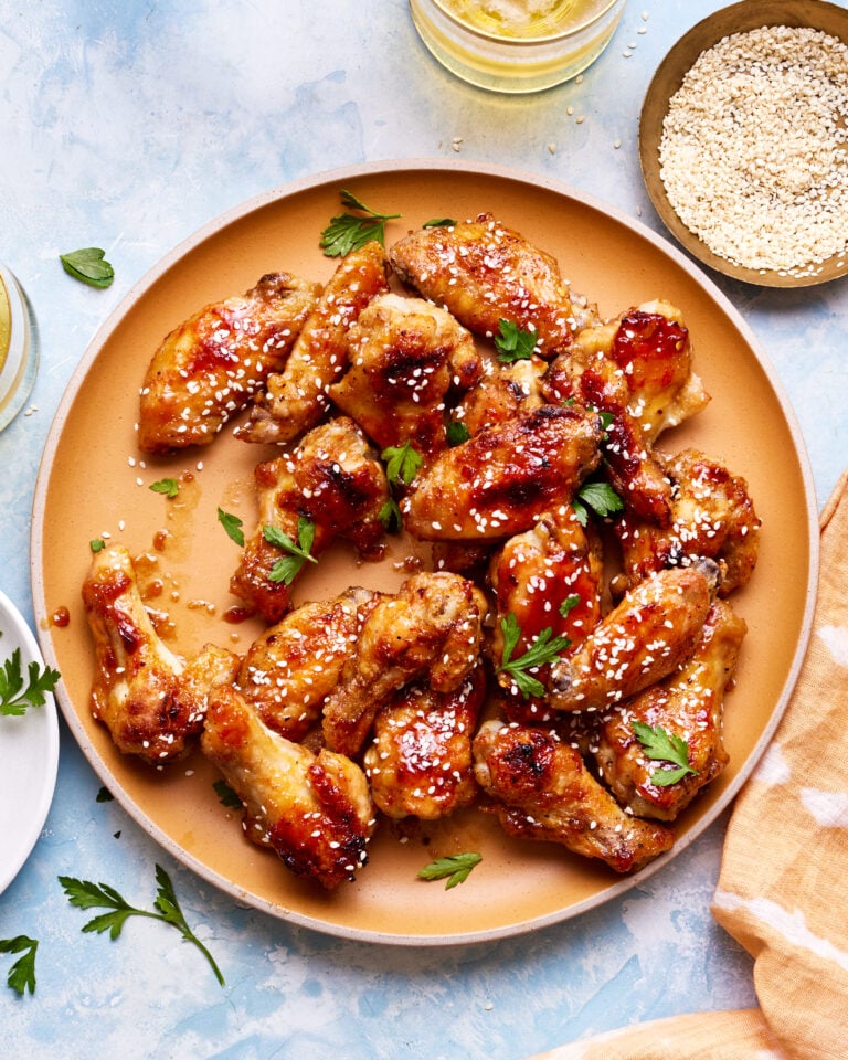 A bowl of the sticky honey garlic chicken wings, sitting on a countertop