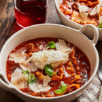 A bowl of the ultimate lasagna soup, sitting on a countertop alongside a larger pot full of the soup