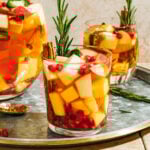 A glass of the spicy white sangria, topped with a sprig of fresh rosemary and a cinnamon stick