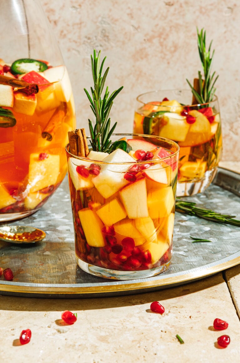 A glass of the spicy white sangria, topped with a sprig of fresh rosemary and a cinnamon stick