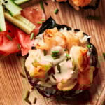 A close-up image of one of the viral shrimp sushi cups, sitting on a plate next to chopped vegetables