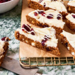 A close-up image of the sliced cranberry bliss bars, sitting on a wire cooling rack