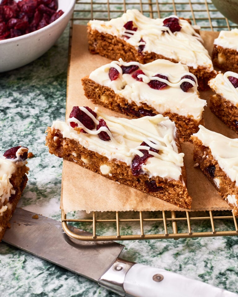A close-up image of the sliced cranberry bliss bars, sitting on a wire cooling rack