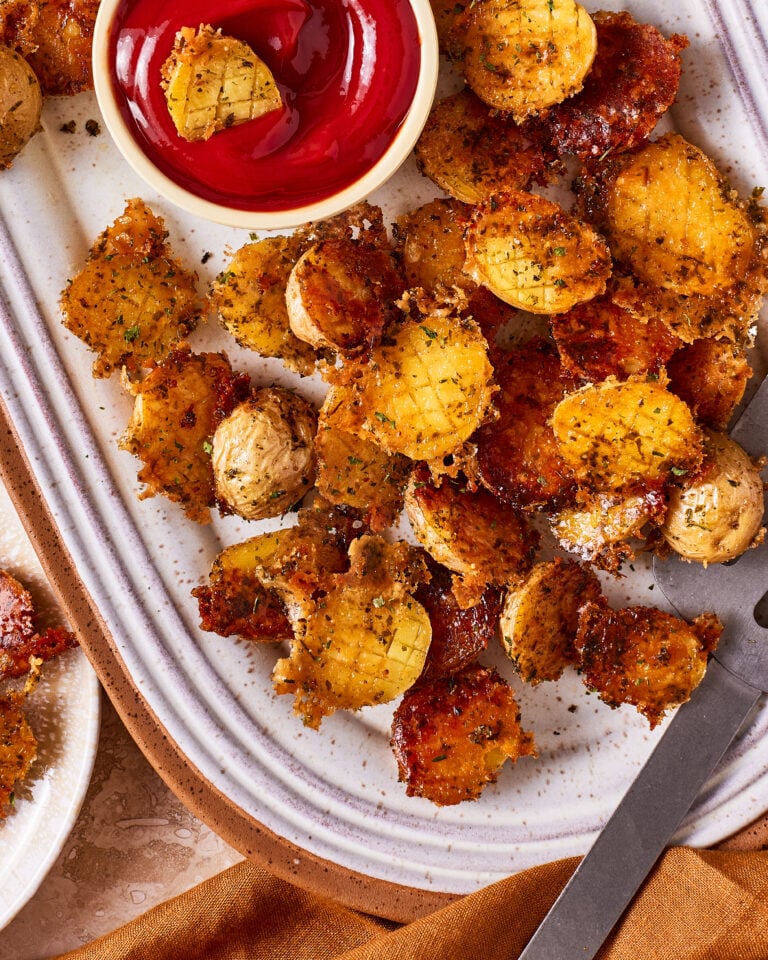 A close-up image of a bowl of the viral crispy parmesan potatoes, sitting on a countertop