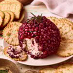 A close-up image of the holiday cheese ball, sitting on a plate next to crackers